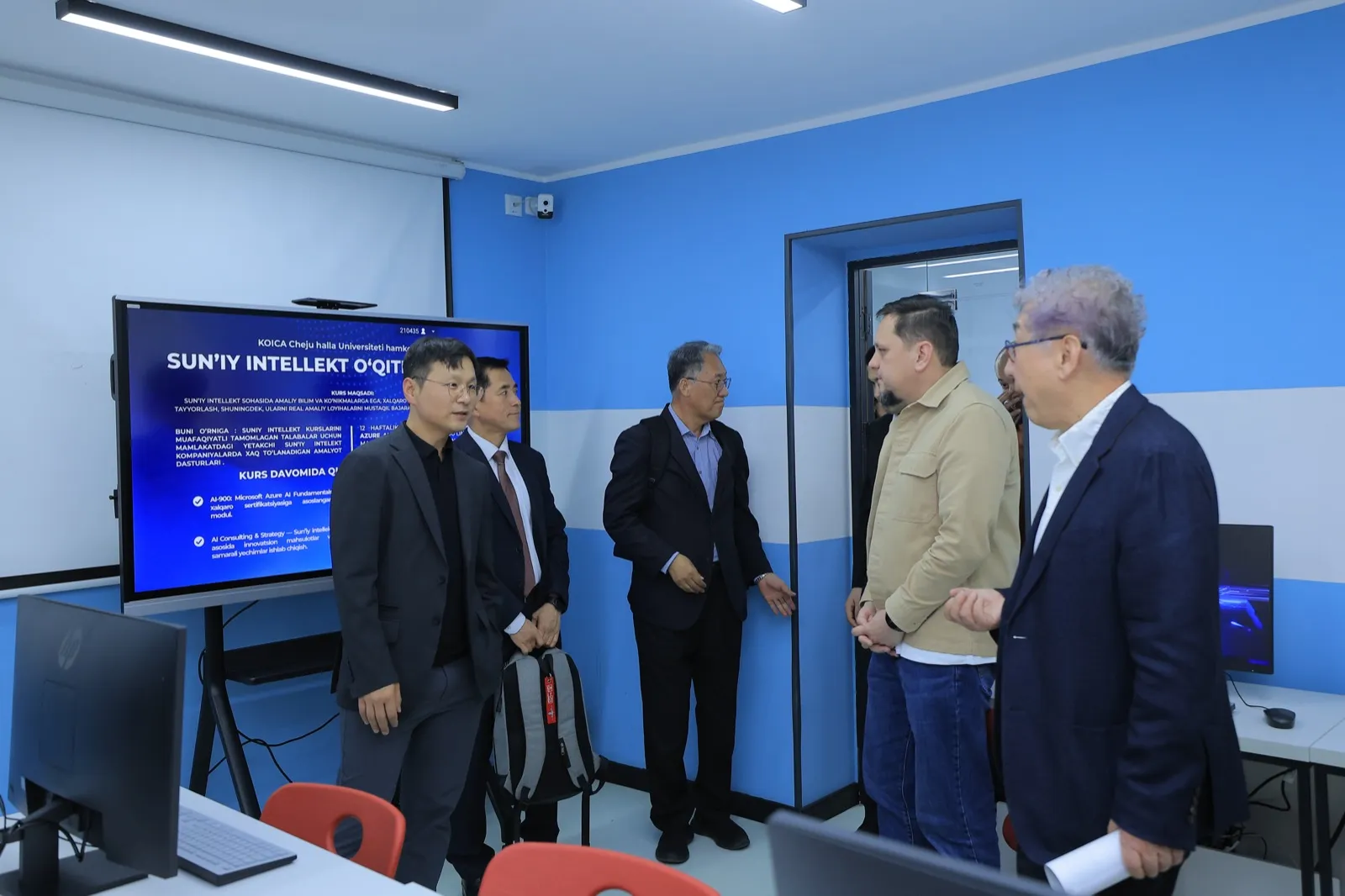 Touring the AI training lab at TIU with course materials displayed in Uzbek