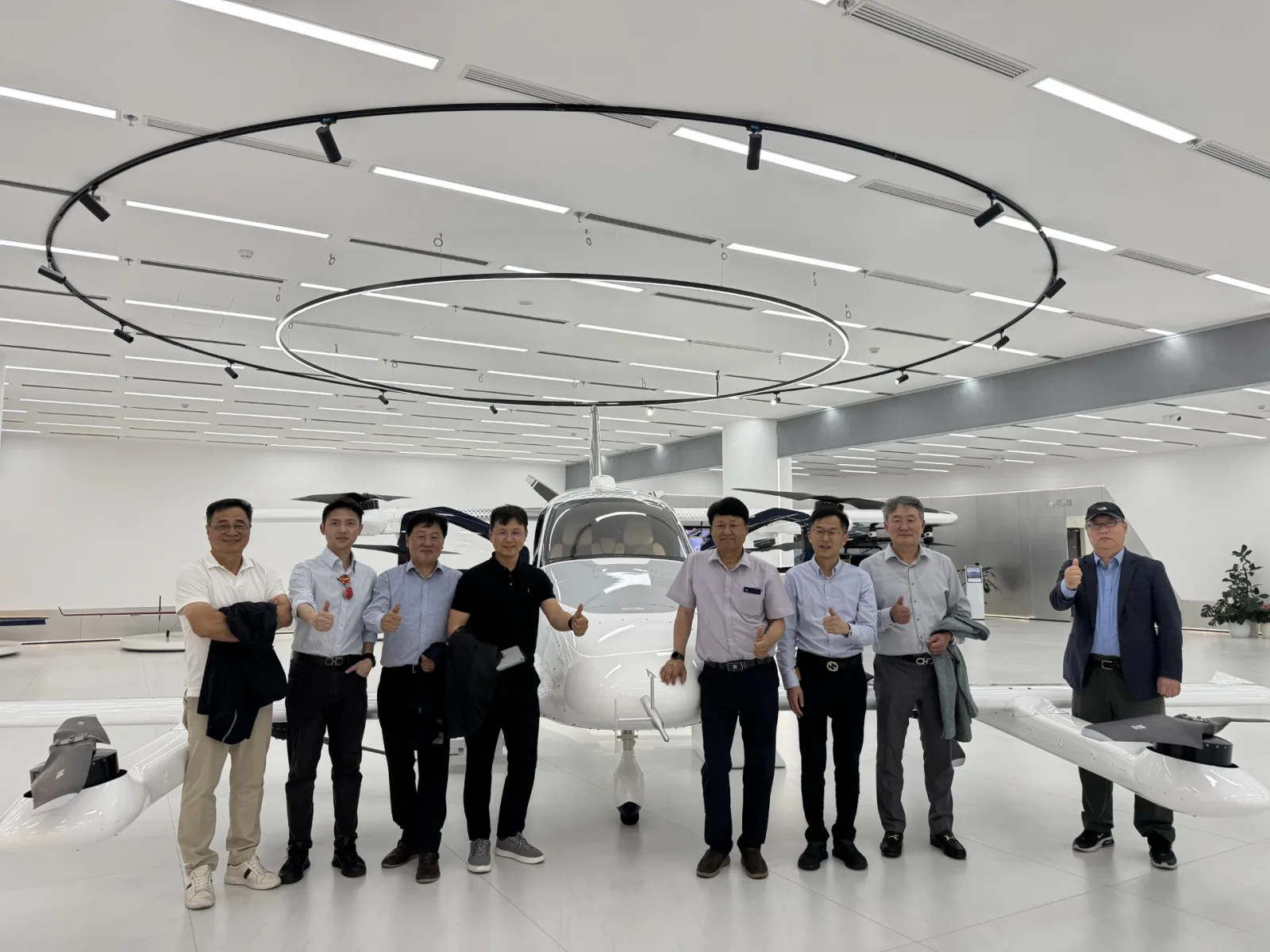Delegation standing beside a white EHang eVTOL aircraft inside the company showroom