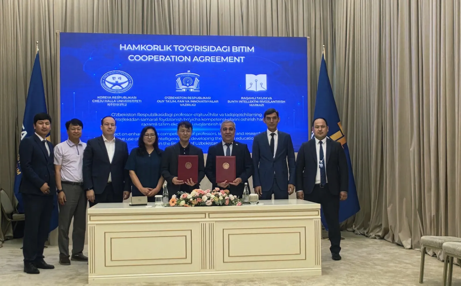The Cheju Halla University and Uzbek delegations behind the signing table at the Central Asian Expocenter, beneath a banner reading "Cooperation Agreement"