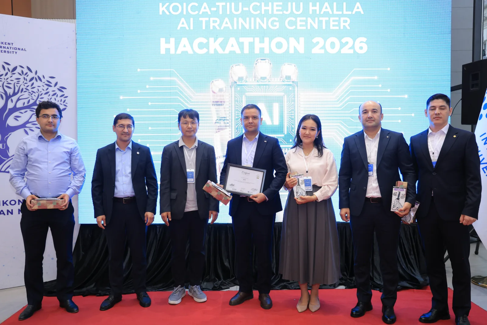 The grand-prize team, Voice the Ballot (Team 04), receiving their award and certificate from the judges — including Cheju Halla University's Young Joon Lee — on the Hackathon 2026 stage