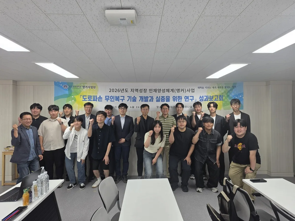 The RovoRoad project team at the Year-1 results report and Year-2 kickoff at Cheju Halla University's K-HighTech Center, beneath a banner for the road-damage unmanned repair research